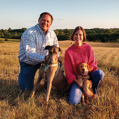 couple in field with 2 dogs